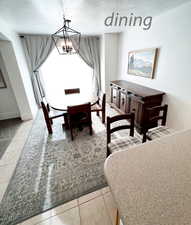 Tiled dining room featuring a textured ceiling and an inviting chandelier