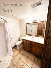 Bathroom featuring a shower with curtain, vanity, a textured ceiling, and toilet