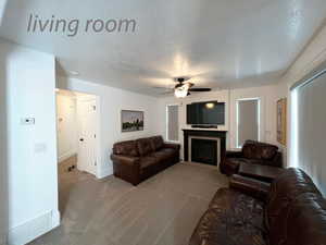 Living room featuring light carpet, ceiling fan, and a textured ceiling