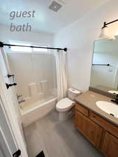 Full bathroom featuring vanity, shower / bath combination with curtain, and toilet