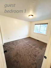 Unfurnished room with a textured ceiling and dark carpet