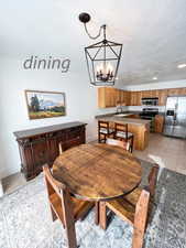 Dining space featuring sink, light tile patterned floors, a textured ceiling, and an inviting chandelier