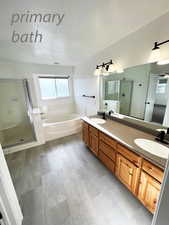 Bathroom with a textured ceiling, vanity, and independent shower and bath