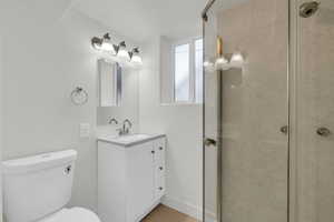 Bathroom with tiled shower, tile patterned floors, vanity, and toilet