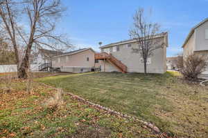 Back of house with a lawn and a deck