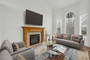 Living room featuring a tile fireplace, lofted ceiling, light hardwood / wood-style flooring, and plenty of natural light