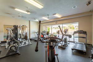 Gym featuring a textured ceiling and ceiling fan