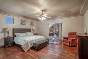 Bedroom featuring a textured ceiling, dark hardwood / wood-style flooring, access to outside, and ceiling fan