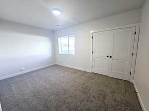 Unfurnished bedroom with dark carpet and a closet