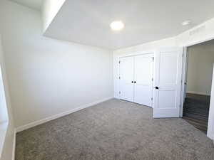 Unfurnished bedroom featuring dark colored carpet and a closet