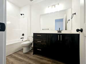 Full bathroom with hardwood / wood-style floors, vanity, toilet, and tub / shower combination