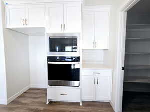 Kitchen featuring white cabinets, stainless steel oven, dark hardwood / wood-style flooring, and built in microwave