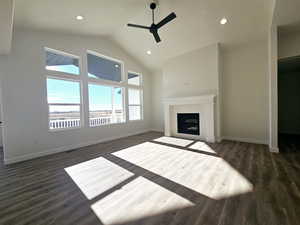 Living room featuring dark hardwood / wood-style flooring, ceiling fan, a fireplace, and high vaulted ceiling