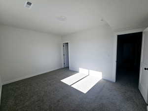 Spare room featuring dark colored carpet