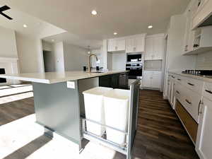 Kitchen with backsplash, white cabinets, sink, an island with sink, and appliances with stainless steel finishes