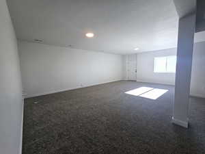 Empty room featuring dark colored carpet and a textured ceiling