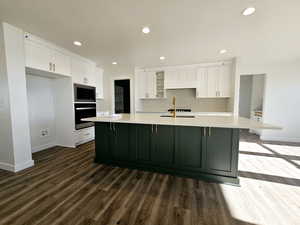 Kitchen featuring wall oven, built in microwave, a large island, and white cabinets