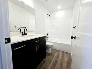 Full bathroom featuring vanity, shower / bathtub combination, toilet, and wood-type flooring