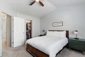 Bedroom featuring lofted ceiling, ceiling fan, a spacious closet, light colored carpet, and a closet