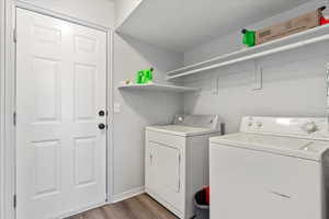 Clothes washing area with washer and dryer and dark hardwood / wood-style flooring