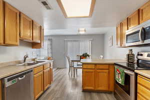 Kitchen featuring sink, light hardwood / wood-style flooring, kitchen peninsula, a textured ceiling, and appliances with stainless steel finishes