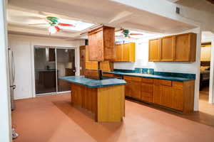 Kitchen with a center island, sink, ceiling fan, beam ceiling, and stainless steel refrigerator