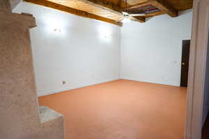 Empty room featuring ceiling fan, beamed ceiling, and wood ceiling