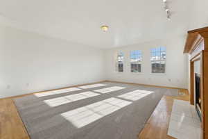 Unfurnished living room with rail lighting and light hardwood / wood-style flooring