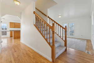 Stairway with hardwood / wood-style flooring and ornamental molding