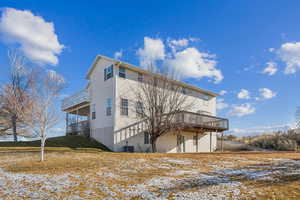 Snow covered house featuring a wooden deck and a yard