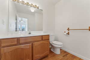 Bathroom with hardwood / wood-style floors, vanity, toilet, and ceiling fan