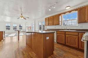 Kitchen featuring sink, dark hardwood / wood-style floors, white dishwasher, a kitchen island, and range