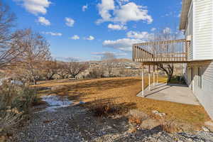 View of yard featuring a wooden deck and a patio area