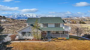 View of front of home featuring a mountain view, a balcony, a front lawn, and covered porch