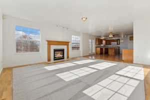 Unfurnished living room with ceiling fan, a high end fireplace, and light hardwood / wood-style floors