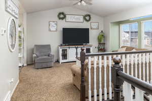 Living room featuring ceiling fan, lofted ceiling, and carpet floors