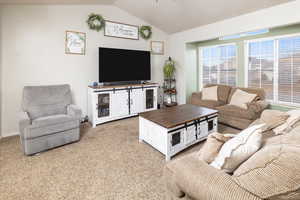 Living room featuring carpet flooring and vaulted ceiling