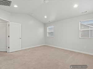 Carpeted spare room with vaulted ceiling