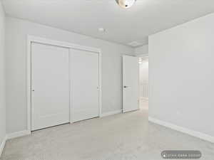 Unfurnished bedroom with light carpet and a closet