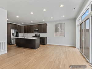 Kitchen featuring a center island with sink, sink, decorative backsplash, appliances with stainless steel finishes, and light hardwood / wood-style floors