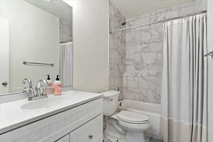 Full bathroom with vanity, toilet, and shower / bathtub combination with curtain