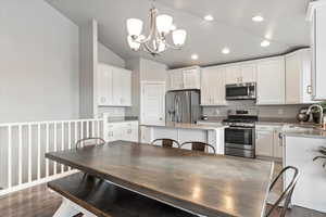 Kitchen with pendant lighting, a center island, sink, vaulted ceiling, and stainless steel appliances