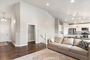 Living room featuring high vaulted ceiling, dark wood-type flooring, and an inviting chandelier