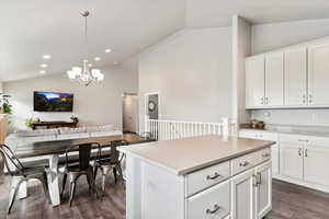 Kitchen with pendant lighting, white cabinets, a center island, dark hardwood / wood-style floors, and lofted ceiling