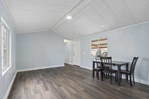 Dining room with dark hardwood / wood-style flooring and lofted ceiling with beams