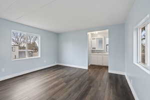 Bedroom with connected bathroom and dark hardwood / wood-style flooring