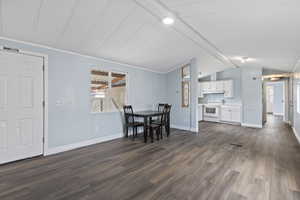 Dining space with vaulted ceiling with beams and dark hardwood / wood-style floors