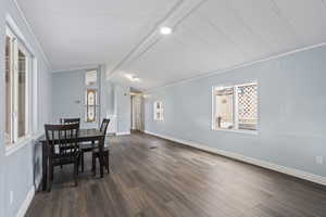 Dining area with lofted ceiling with beams, dark hardwood / wood-style floors, and crown molding