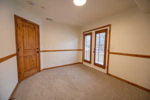 Carpeted spare room featuring french doors