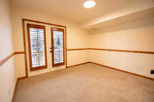 Unfurnished room featuring french doors and carpet